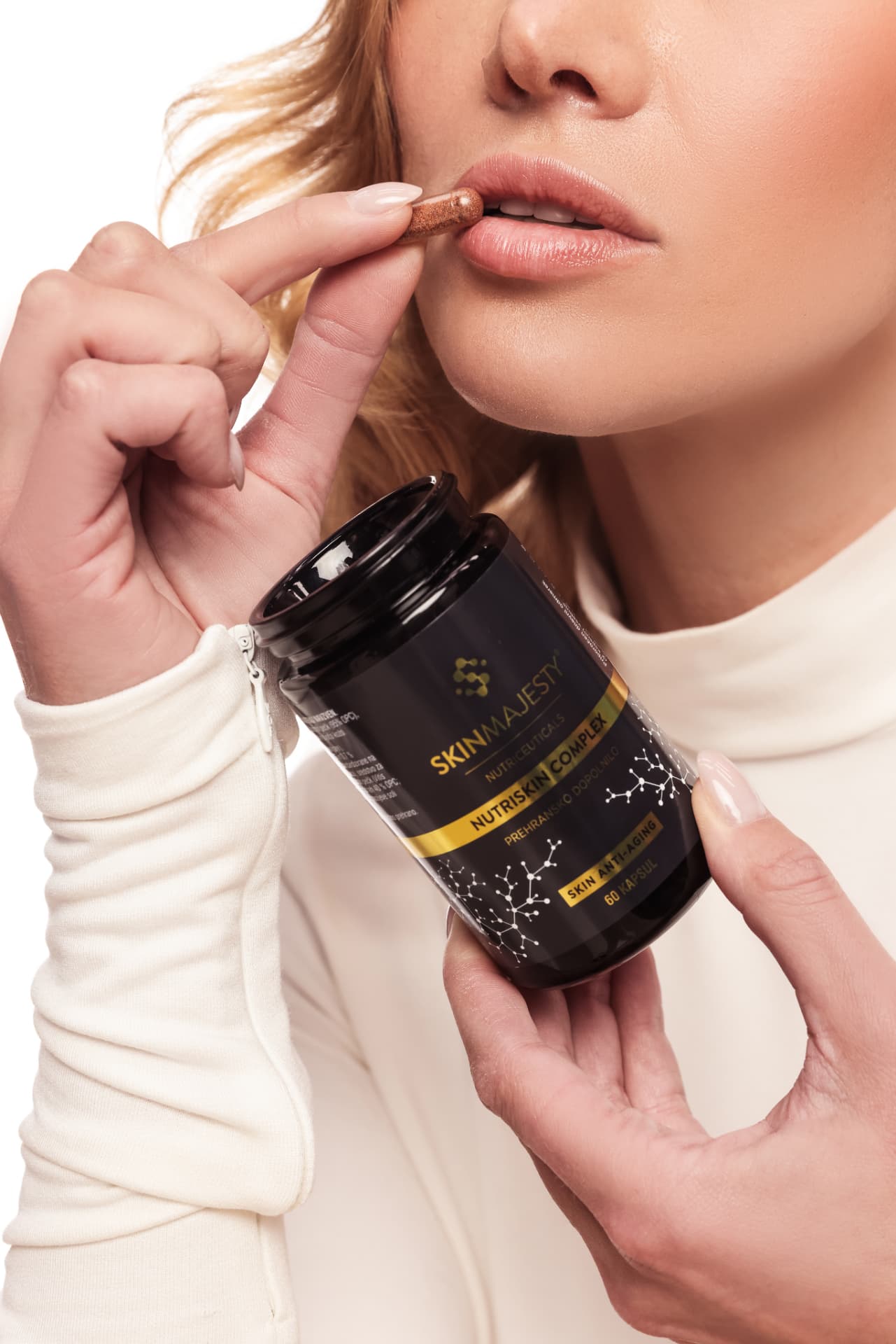 Dve kapsuli Nutriskin Complex na dlani nad odprto embalažo